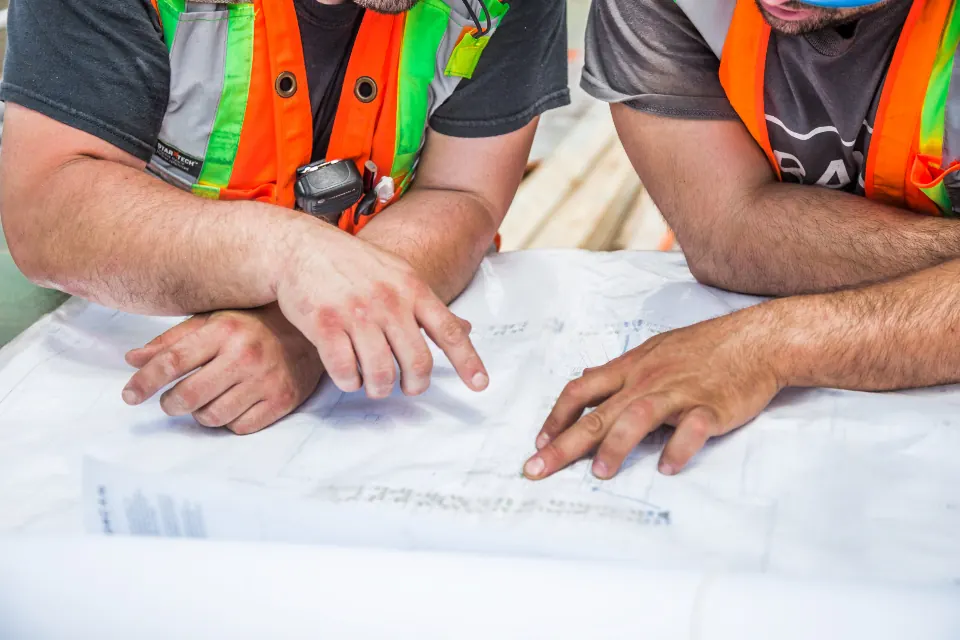 Deux professionnels du bâtiment étudient des plans de travaux